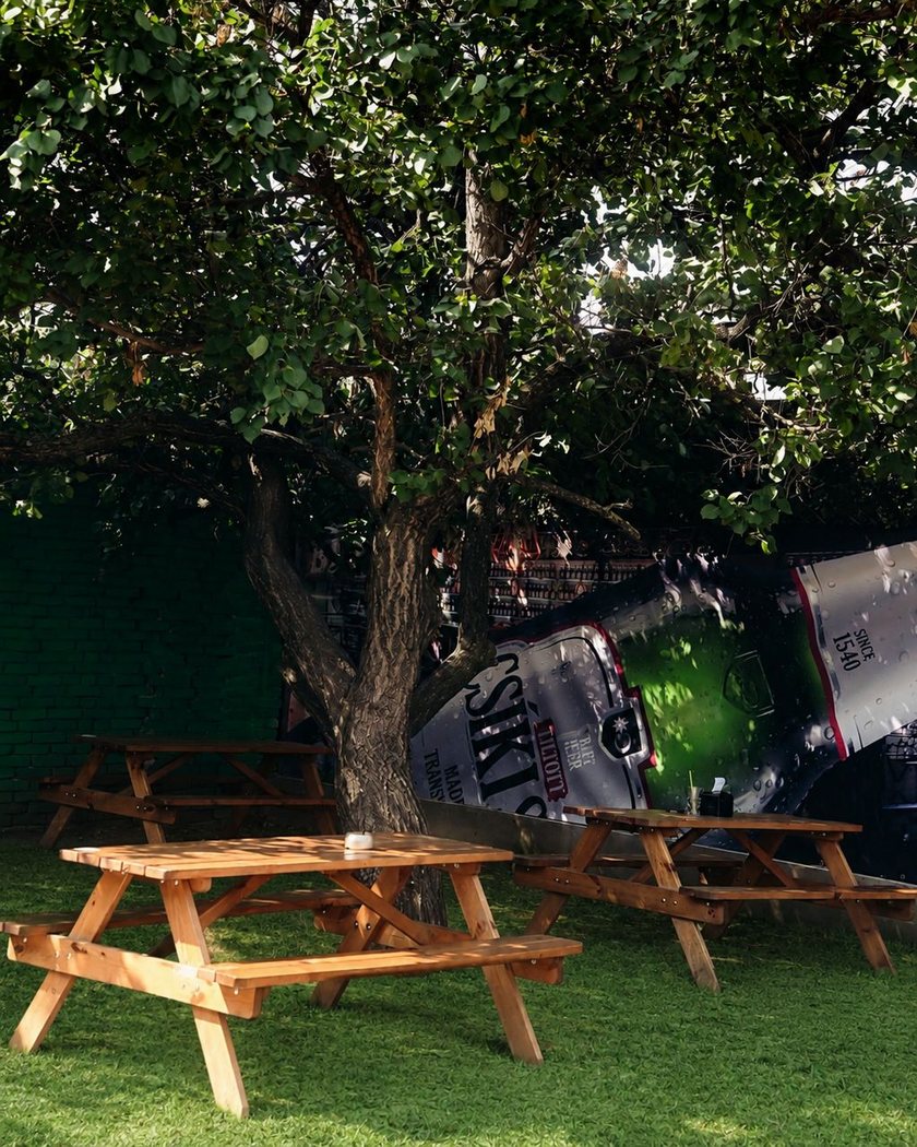 Grădina restaurantului, cu mese de picnic la umbra unui copac bătrân