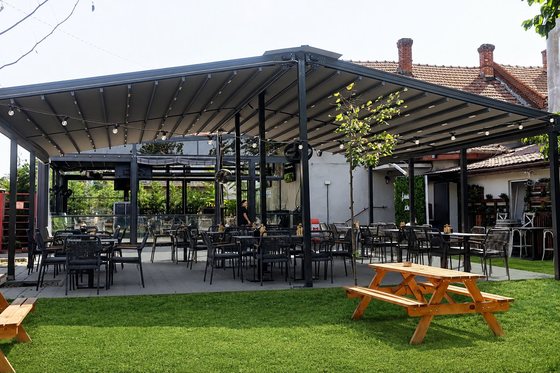 Grădina cu iarbă, mese de picnic și terasa acoperită